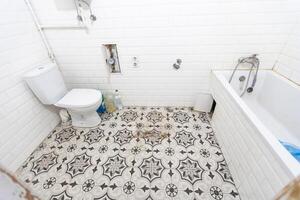 interieur van versmallen toilet met muur hing toilet met wit muren en geruit verdieping foto