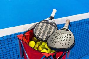 peddelen tennis racket en ballen Aan de blauw peddelen rechtbank foto