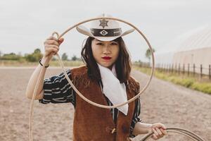 mooi Chinese veedrijfster het werpen de lasso in een paard paddock foto