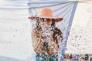 mooi vrouw met kleurrijk rietje hoed blazen confetti foto