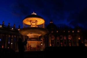 nacht beeld van een toerist fotograferen een van de verlichte fonteinen in st. peter's plein foto