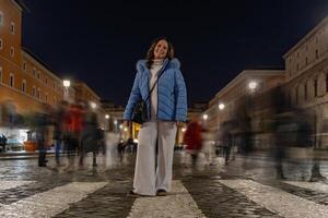 vrouw toerist poseren tussen wazig mensen wandelen Bij nacht Aan een straat in voorkant van de Vaticaan in Rome foto