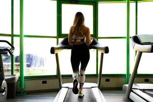 jong blond vrouw rennen in sportkleding Aan de loopband in een Sportschool foto