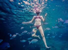 meisje aan het snorkelen en omringd met chopa-vissen foto