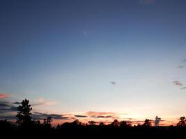 spectaculair zonsondergang over, oranje zon stijgende lijn omhoog over- de horizon foto