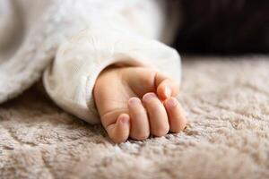een links hand- van slapen Aziatisch baby Aan de tapijt foto