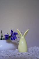 minimalistische irissen Aan wit keramisch vaas Aan tafel met Pasen konijn foto