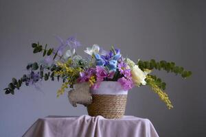 Pasen bloemen arrangement met twee blauw Pasen konijntjes in een rieten mand foto