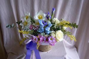 Pasen bloemen arrangement met twee blauw Pasen konijntjes in een rieten mand foto