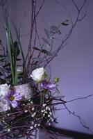 Pasen lauwerkrans, nest van wilg takken en bloemen versierd met eieren en glas test buizen in een transparant vaas foto