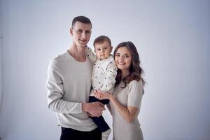 een minimalistische portret van een moeder, vader en hun twee jaar oud zoon Aan een wit achtergrond foto