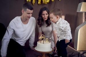 emotioneel ouders kijk maar net zo hun zoon slagen uit de kaarsen Aan de verjaardag taart foto