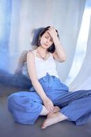 jong tiener- meisje vechten hersenen kanker Bij foto schieten in studio zittend Aan vloer, leunend tegen metaal muur, reflectie
