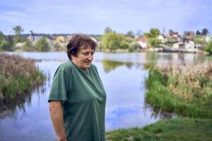 oud vrouw aan het doen opdrachten in de ochtend- Aan de rivier- bank, een fiets en een yogamat De volgende naar haar foto