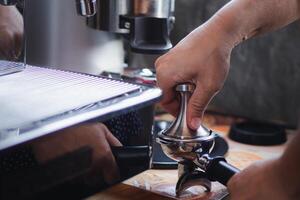 detailopname van handen barista persen grond koffie gebruik makend van een knoeien. de werkwijze van maken koffie stap door stap foto