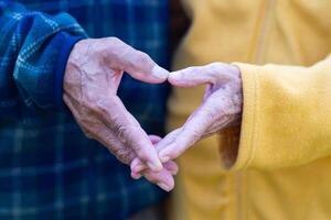detailopname van de ouderen koppel hand- tonen een hartvormig symbool met vingers. concept van oud mensen en liefde foto