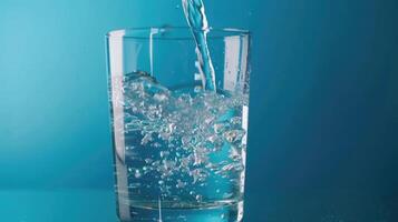 water uit fles in glas gieten op blauwe achtergrond foto