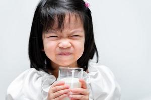 schattig meisje drinkt melk uit glas. kinderen drinken graag melk. 4-jarige jongen. geïsoleerde witte achtergrond. foto