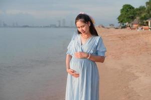 zwangere vrouw die gelukkig naar de zee reist foto