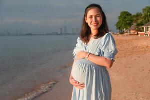 zwangere vrouw die gelukkig naar de zee reist foto