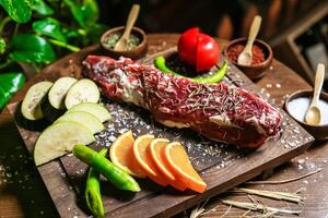 houten snijdend bord met vers vlees en geassorteerd groenten foto
