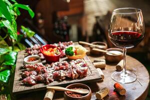 overvloedig houten tafel met geassorteerd voedsel en glas van wijn foto