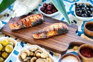 houten snijdend bord met vis en kommen van olijven foto