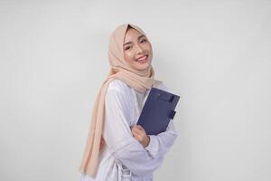 glimlachen jong Aziatisch moslim vrouw vervelend wit jurk en hijab Holding een document, geïsoleerd door wit achtergrond. Ramadan en eid mubarak concept foto