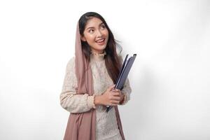 portret van Aziatisch moslim vrouw in hoofddoek sluier hijab staand en glimlachen gelukkig terwijl Holding een document kaart. Ramadan concept foto