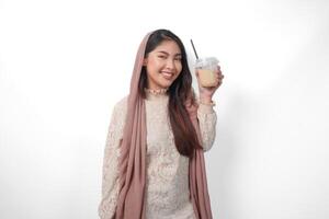 glimlachen Aziatisch moslim vrouw in hoofddoek sluier hijab Holding koffie in een plastic kop aan het wachten voor iftar naar drankje. Ramadan concept foto