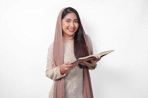 portret van een jong Aziatisch moslim vrouw in sluier hijab glimlachen naar de camera terwijl Holding al koran. Ramadan en eid mubarak concept foto