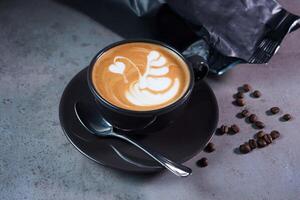 heet molens latte kunst portie in koffie kop met lepel en bonen kant visie Aan grijs achtergrond foto