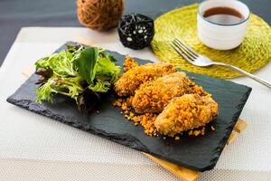 tyfoon onderdak kip vleugel met salade geserveerd Aan snijdend bord geïsoleerd Aan servet kant visie van Fast food foto