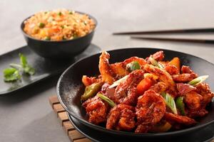 szechuan garnaal omvatten klok peper, tomaat, voorjaar ui met schezwan gebakken rijst- en eetstokjes geserveerd in kom top visie van Chinese voedsel foto