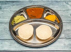 podi idli thali met kerrie geserveerd in schotel geïsoleerd Aan houten tafel top visie van Indisch pittig voedsel foto