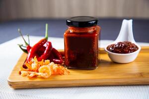 eigengemaakt vis Chili saus pot met rood peper geïsoleerd Aan houten bord kant visie Aan achtergrond foto