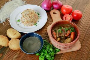 kebab braadpan met aardappel, tomaat, koriander, ui geserveerd in schotel geïsoleerd Aan houten tafel kant visie van Arabisch voedsel foto