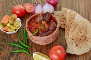 okra braadpan met vlees, ui, tomaat, citroen en augurk geserveerd in schotel geïsoleerd Aan houten tafel kant visie van Arabisch voedsel foto