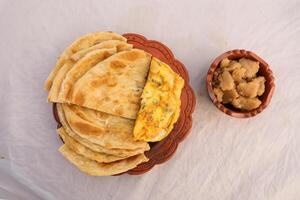 desi ontbijt omelet, halwa en paratha geserveerd in schotel geïsoleerd Aan achtergrond top visie van banglades ontbijt foto