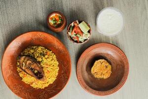 hilsa kichuri combo met salade, aubergine, Borhani en boondi hondsdolheid geserveerd in schotel geïsoleerd Aan mat top visie van Indisch en bangladesh voedsel foto