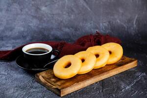 duidelijk donuts met kop van zwart koffie geserveerd Aan houten bord geïsoleerd Aan servet kant visie van gebakken voedsel ontbijt Aan tafel foto
