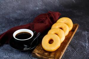 duidelijk donuts met kop van zwart koffie geserveerd Aan houten bord geïsoleerd Aan servet kant visie van gebakken voedsel ontbijt Aan tafel foto