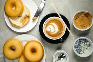 heet butterscotch latte kunst koffie geserveerd in kop met duidelijk donuts, suiker en mes geïsoleerd Aan servet top visie cafe ontbijt foto