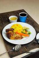 rijst- met kip gebraden maaltijd met salade geserveerd in bord met saus, verkoudheid drankje, lepel en vork geïsoleerd Aan houten bord kant visie van Thais voedsel foto