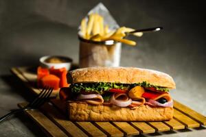 ciabatta gerookt ham belegd broodje geïsoleerd Aan houten met mayonaise dip en Frans Patat emmer bord kant visie van Italiaans snel voedsel Aan grijs achtergrond foto