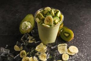 kiwi en banaan milkshake met ijs kubus geserveerd in beschikbaar glas met ijs kubus geïsoleerd Aan tafel kant visie van gezond ochtend- melk schudden drinken foto