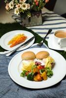 ei Benedict schuif met groente salade omvatten tomaat, aardappel, sla blad en wortel met thee, koffie, en zoet meloen geserveerd Aan voedsel tafel top visie gezond Engels ontbijt foto