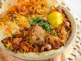 hyderabadi kip biryani met tomaat, koriander, citroen, cachou noot en brood dum geserveerd in koper pot schotel geïsoleerd Aan houten tafel top visie Arabisch pittig voedsel foto