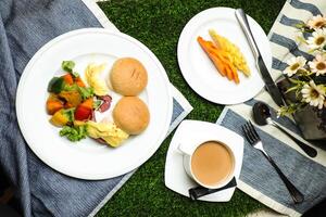 ei Benedict schuif met groente salade omvatten tomaat, aardappel, sla blad en wortel met thee, koffie, en zoet meloen geserveerd Aan voedsel tafel top visie gezond Engels ontbijt foto