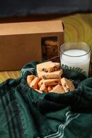knapperig koekjes biscuits geserveerd in bord met koekje doos en glas van melk geïsoleerd Aan tafel kant visie van Amerikaans cafe gebakken voedsel foto